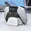 A PlayStation PS5 controller alarm clock is displayed on its charging stand on a desk. Náhled obrázku produktu
