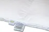 A close-up of a white down comforter with tags attached. Produktbild-Vorschau