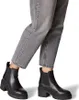 A person wearing grey jeans and black ankle boots. Produktbild-Vorschau