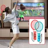 A man playing a video game on a TV, holding a tennis racket accessory. The game displayed on the TV is a tennis game. In the foreground, there is a close-up of two tennis racket accessories with controllers attached. Produktbild-Vorschau