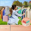 A woman is hanging clothes on a drying rack outdoors. Produktbild-Vorschau