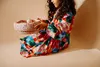 A child sitting on the floor, holding a colorful bowl with sprinkles and a ball inside. Produktbild-Vorschau