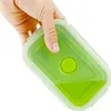 A hand holding a green silicone food container. Náhled obrázku produktu