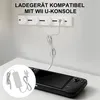 A Wii U Gamepad charger and AC adapter are shown connected to a power strip on a wall, with the Gamepad itself resting on a table. Produktbild-Vorschau