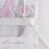 A close-up view of a sheer curtain with a floral print and a pull cord. Produktbild-Vorschau