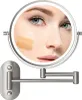 A close-up reflection of a woman's face with makeup swatches in a lighted makeup mirror. Produktbild-Vorschau