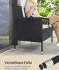 A person is sitting on a black rattan chair with a cushion, holding a mug, on a patio. Produktbild-Vorschau