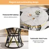 A round dining table with a marble-like pattern and a black metal base, shown in a room setting with chairs. Náhled obrázku produktu