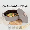 A Dutch oven filled with food, with its lid open, placed on a wooden board. Náhľad obrázku produktu