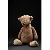 A brown teddy bear sits on a black surface against a black background. Podgląd zdjęcia produktu