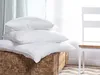 Three white pillows are stacked on a wooden chest in front of a window with sheer curtains. Podgląd zdjęcia produktu