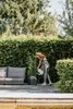 A woman watering plants in a garden next to a sofa. Produktbild-Vorschau