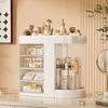 A white rotating makeup organizer filled with various cosmetic products sits on a desk. Náhled obrázku produktu