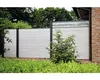 A modern fence with a clear top section, set in a garden with lush green bushes and trees. Produktbild-Vorschau