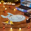 A Star Trek model spaceship is displayed on a wooden surface, surrounded by Christmas lights and decorations. Podgląd zdjęcia produktu