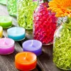 A collection of colorful tea lights and glass vases filled with decorative water beads on a wooden surface. Produktbild-Vorschau
