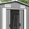 Close-up view of the entrance to a gray metal storage shed, showing ventilation grates and an open doorway with a ladder and shovel inside. Náhled obrázku produktu
