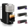 A Nespresso coffee machine with a cup of coffee and several boxes of coffee capsules. Produktbild-Vorschau