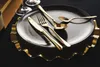 A close-up shot of gold cutlery set on a black plate and a decorative gold charger plate. Anteprima dell’immagine prodotto