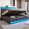 A modern bedroom with a grey upholstered bed frame, open to reveal storage space underneath. Blue LED lights illuminate the headboard and base of the bed. Náhľad obrázku produktu