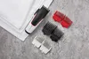 A hair clipper and its attachments are laid out on a textured surface next to a stack of white towels. Podgląd zdjęcia produktu