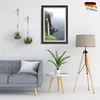 A living room scene with a sofa, a framed picture of a waterfall, hanging terrariums, a plant on a side table, and a floor lamp. Produktbild-Vorschau