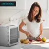 A woman is preparing fruit in a kitchen next to a dehydrator. Podgląd zdjęcia produktu