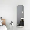 A full-length mirror is shown in a bedroom setting, reflecting a bedside table with a vase of flowers and a woven basket. Voir les images du produit