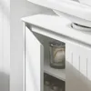 A close-up view of a white bathroom vanity cabinet with one door slightly ajar, revealing a glass jar with cotton balls inside. Produktbild-Vorschau