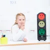 A young girl is making a shushing gesture next to a noise level meter with different colored lights and smiley faces. Voir les images du produit