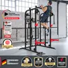 A man is performing a pull-up on a large, black and red home gym machine in a bright, industrial-style room. Produktbild-Vorschau