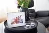 A framed photo sits on a tray with candles and flowers, next to a chair. Produktbild-Vorschau