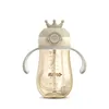 A baby bottle with a straw and handles, designed to look like a crown on top. Produktbild-Vorschau