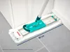 A mop head with a turquoise handle is shown cleaning a corner of a room next to a white cabinet. Produktbild-Vorschau