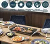 A table set for a meal with a grill in the center, featuring food and plates. Voir les images du produit