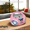 A pink portable CD player with a radio is placed on a wooden table in front of a large window with a view of trees and mountains. Batteries are shown in the foreground. Voir les images du produit