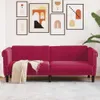 A red velvet sofa with a beige throw blanket is displayed against a white wall with framed artwork. Produktbild-Vorschau