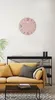 A living room scene with a pink wall clock, a yellow sofa, and a black shelf unit. Produktbild-Vorschau