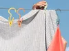 A person is hanging laundry on a clothesline on a sunny day. Anteprima dell’immagine prodotto