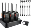 A set of six black walkie-talkies with orange accents are neatly arranged in a black charging base. Six black earpieces with microphones are also displayed to the right of the walkie-talkies. A black power adapter is connected to the charging base. Náhled obrázku produktu