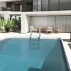 A swimming pool with a ladder and outdoor furniture. Produktbild-Vorschau