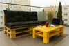 A balcony with outdoor furniture, including a pallet sofa and a yellow coffee table. Produktbild-Vorschau