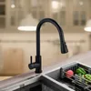 A modern kitchen sink area with a black faucet and a dish rack filled with fruits and vegetables. Náhľad obrázku produktu