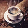 A clock face designed to look like a coffee cup with coffee beans and a burlap sack in the background. Produktbild-Vorschau