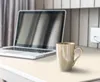 A laptop and a mug on a light-colored desk. Produktbild-Vorschau