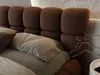 A close-up view of a brown upholstered bed with pillows and a decorative branch. Produktbild-Vorschau