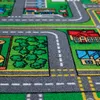 A close-up view of a children's play rug depicting a town with roads, houses, and trees. Produktbild-Vorschau