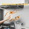 A person cleaning oil stains on a kitchen backsplash with a white cloth. Produktbild-Vorschau