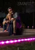A couple embracing outdoors at night, illuminated by pink LED lights. Produktbild-Vorschau