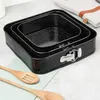 A set of three black square baking pans with a speckled granite coating, nested together. Two wooden spoons are placed in front of the pans on a light green cloth. A light-colored oven mitt with brown leather accents is visible in the background. Anteprima dell’immagine prodotto